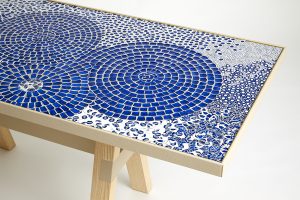 Mathilde Jonquière, mosaic artist, June 2023, original creation of a “Bleu d’ailleurs” table for Petit H, dimensions 1.70m x 070m. Infinite round shapes are drawn, superimposed, intertwined and juxtaposed in harmonious interstices. © Eugenia Sierko, Hermès